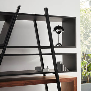 a small glimmer of leafy greenery can be seen through an open back designer bookshelf