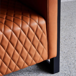 Supple tan leather quilting draws attention on this close up detail of a modern armchair