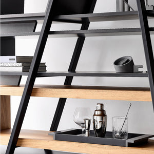 A triangle black frame is the focal point of a designer bookshelf crafted from oak and walnut woods.