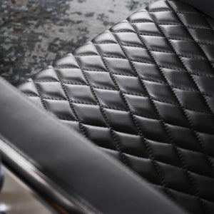 A close up detail of the pillowing leather stitches on a modern armchair in black 